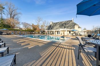 a swimming pool with chairs and umbrellas in front of a house at Ashton Creek, Chester